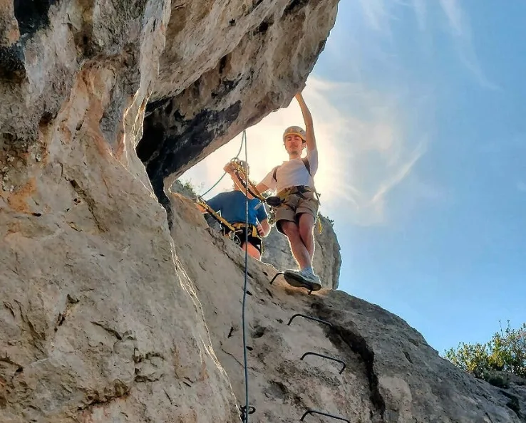 Florian en action en falaise, encadrant un grimpeur